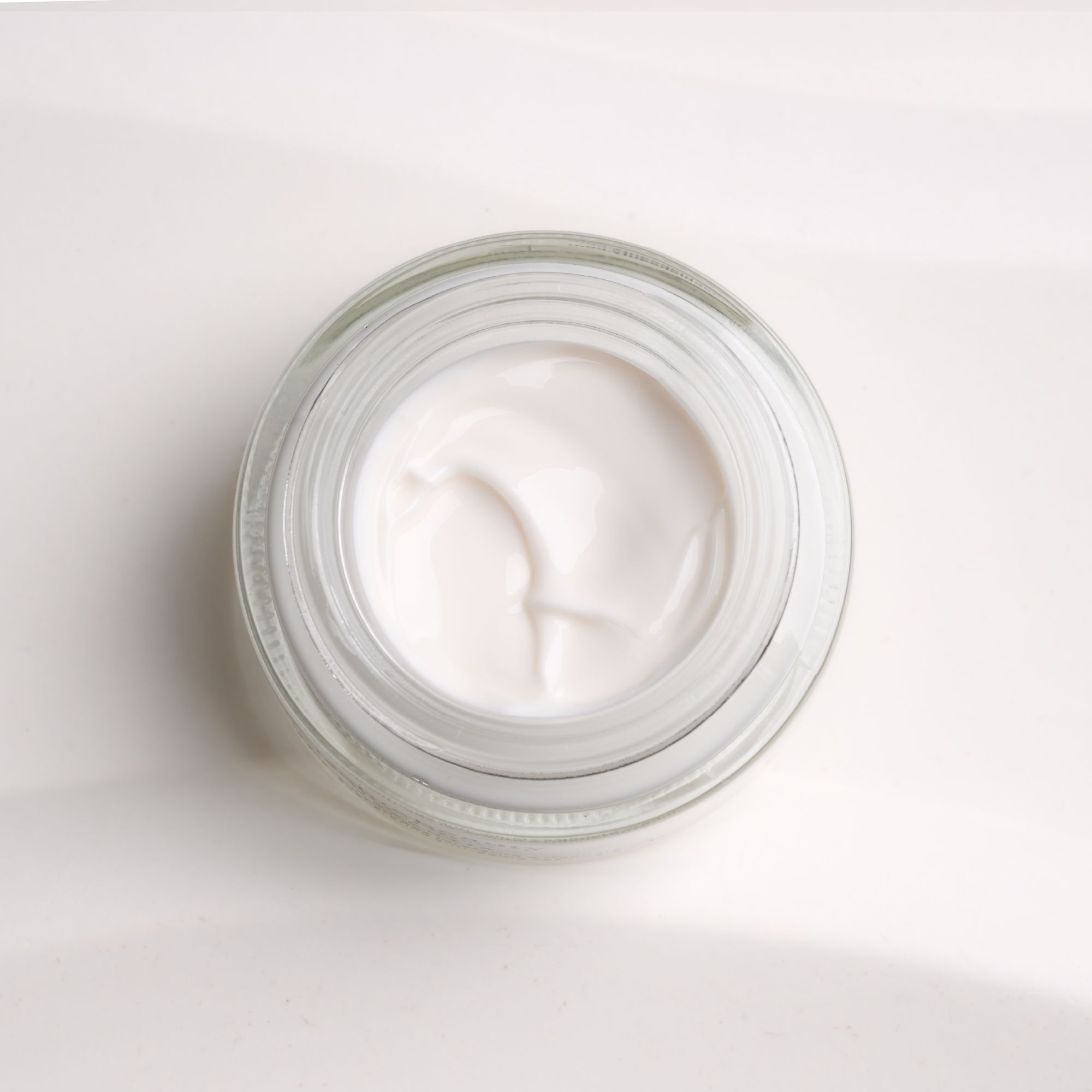 Offene Creme-Dose. Cremefarbene Creme in einem Glasbehälter. Draufsicht.