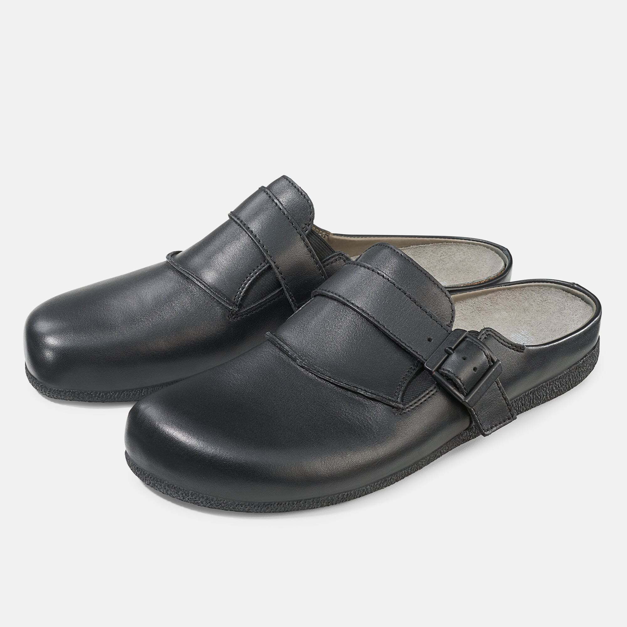 Schwarze Pantoletten mit breitem Riemen und Schnalle. Innenfutter hellgrau. Zwei Schuhe nebeneinander, leicht schräg gestellt.