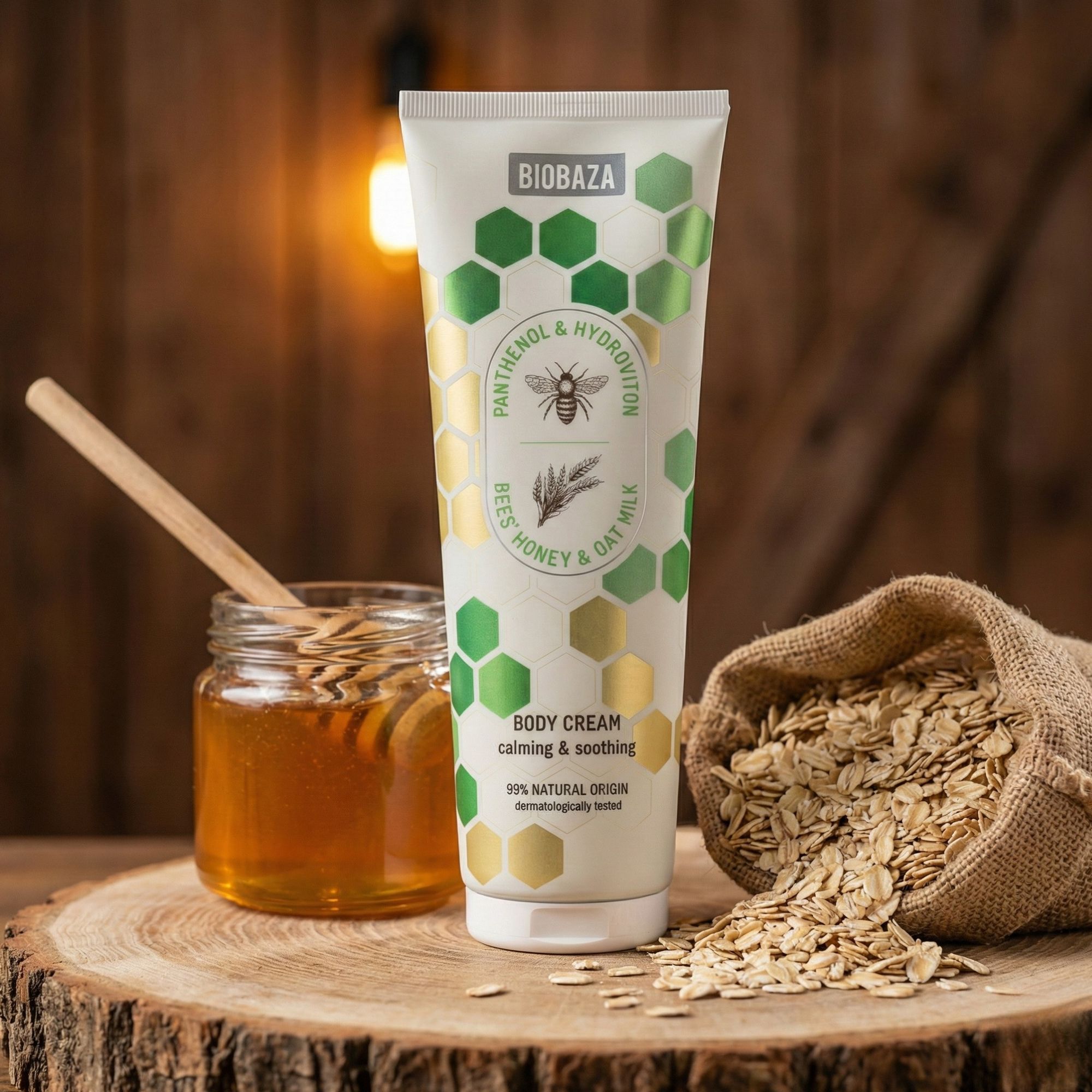 Creme-Tube mit Honig, Hafer und Bienen-Motiv. Daneben Honigglas, Haferflocken in Leinensack auf Holz. Natürliche Inhaltsstoffe.