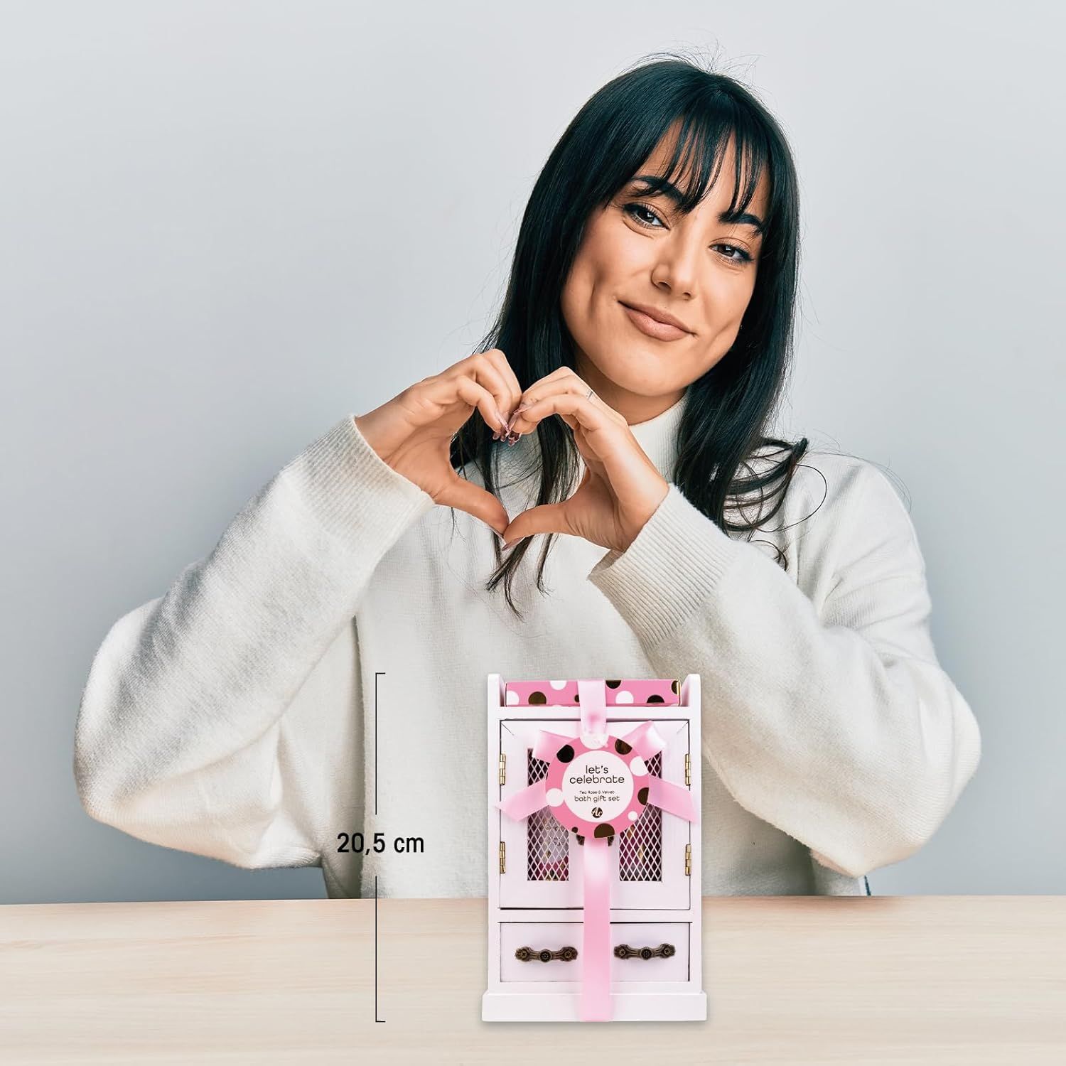 Frau formt Herz mit Händen. Geschenkset in weißem Schrank, mit rosa Schleife. Abmessung: 20,5 cm.