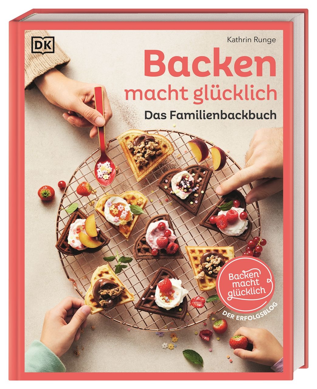 Buch "Backen macht glücklich". Roter Einband, Titel in Rosa. Waffeln auf Gitter, Hände mit Zutaten. DK-Logo.