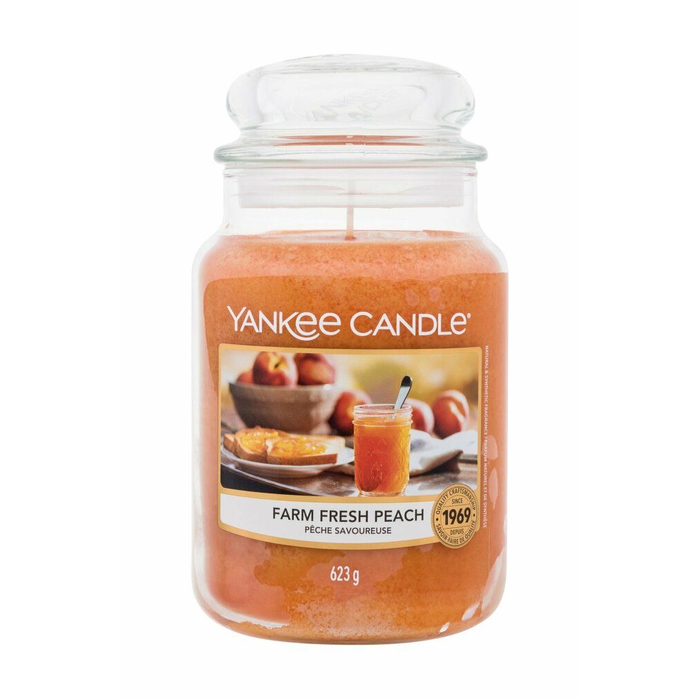 Duftkerze mit Deckel. Aufkleber mit Pfirsich-Motiv und Schriftzug. Aufschrift: Yankee Candle, Farm Fresh Peach, 623g.