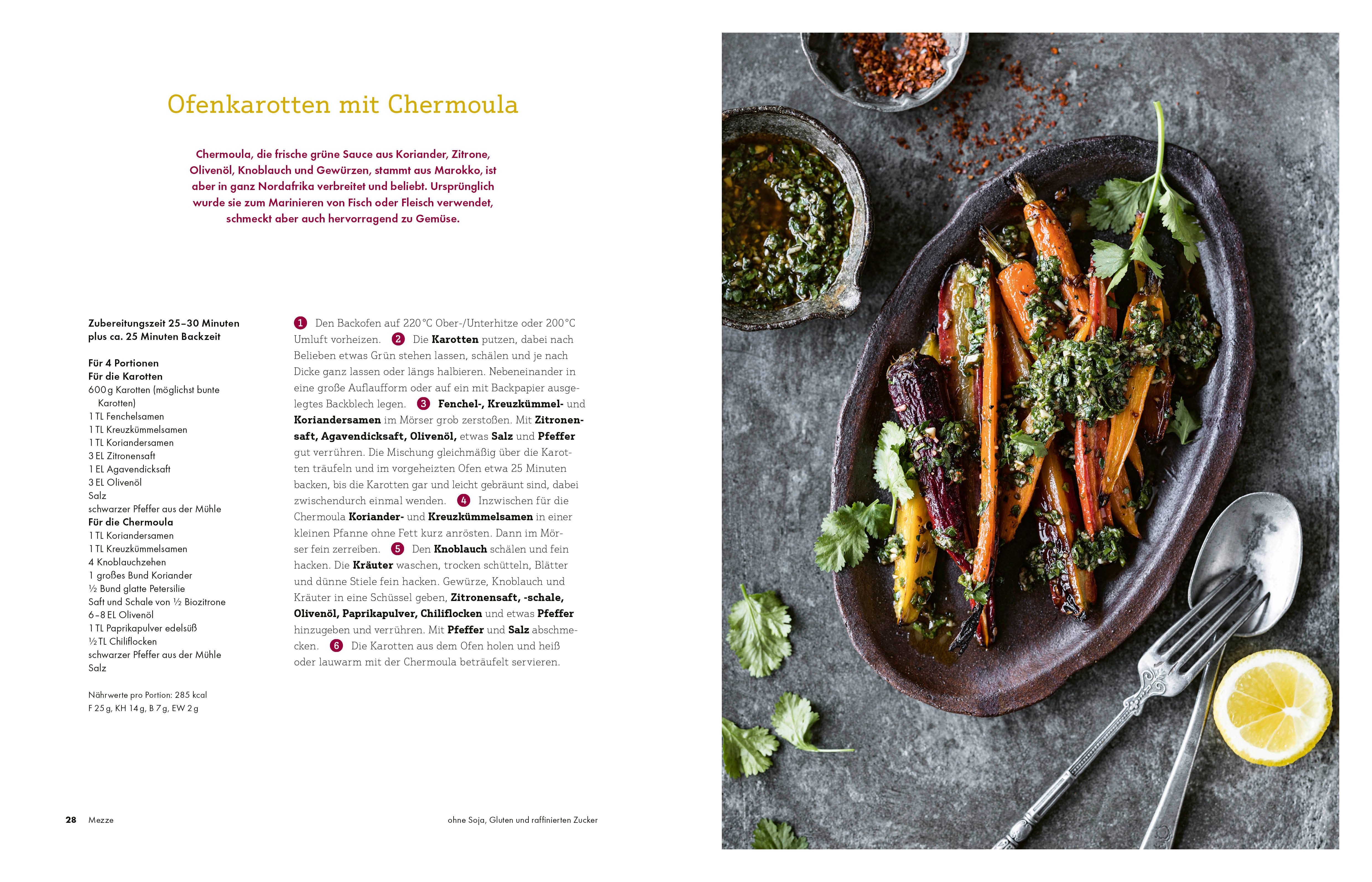 Gebratene Karotten mit Kräutern auf einem Teller. Dazu Besteck und Zitrone. Rezept aus einem Kochbuch.