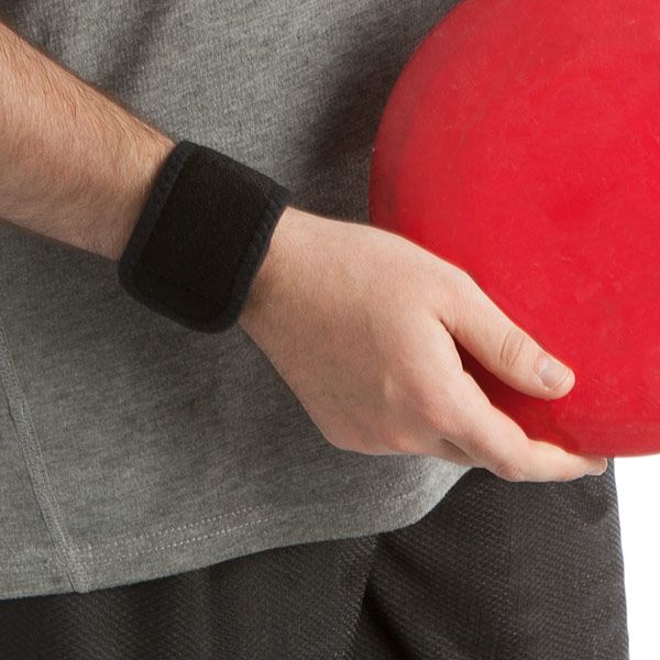 Person trägt schwarze Handgelenkbandage. Hält roten Ball. Graues Shirt, schwarze Hose.