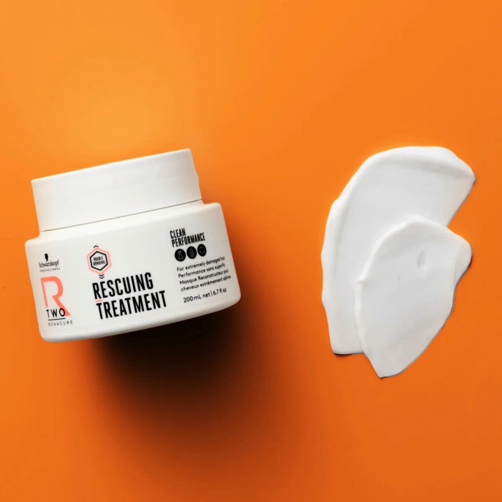 Weißes Tiegel und Produktprobe auf orangefarbenem Hintergrund. Text: R-TWO Rescuing Treatment, 200 ml. Schwarzkopf Logo.
