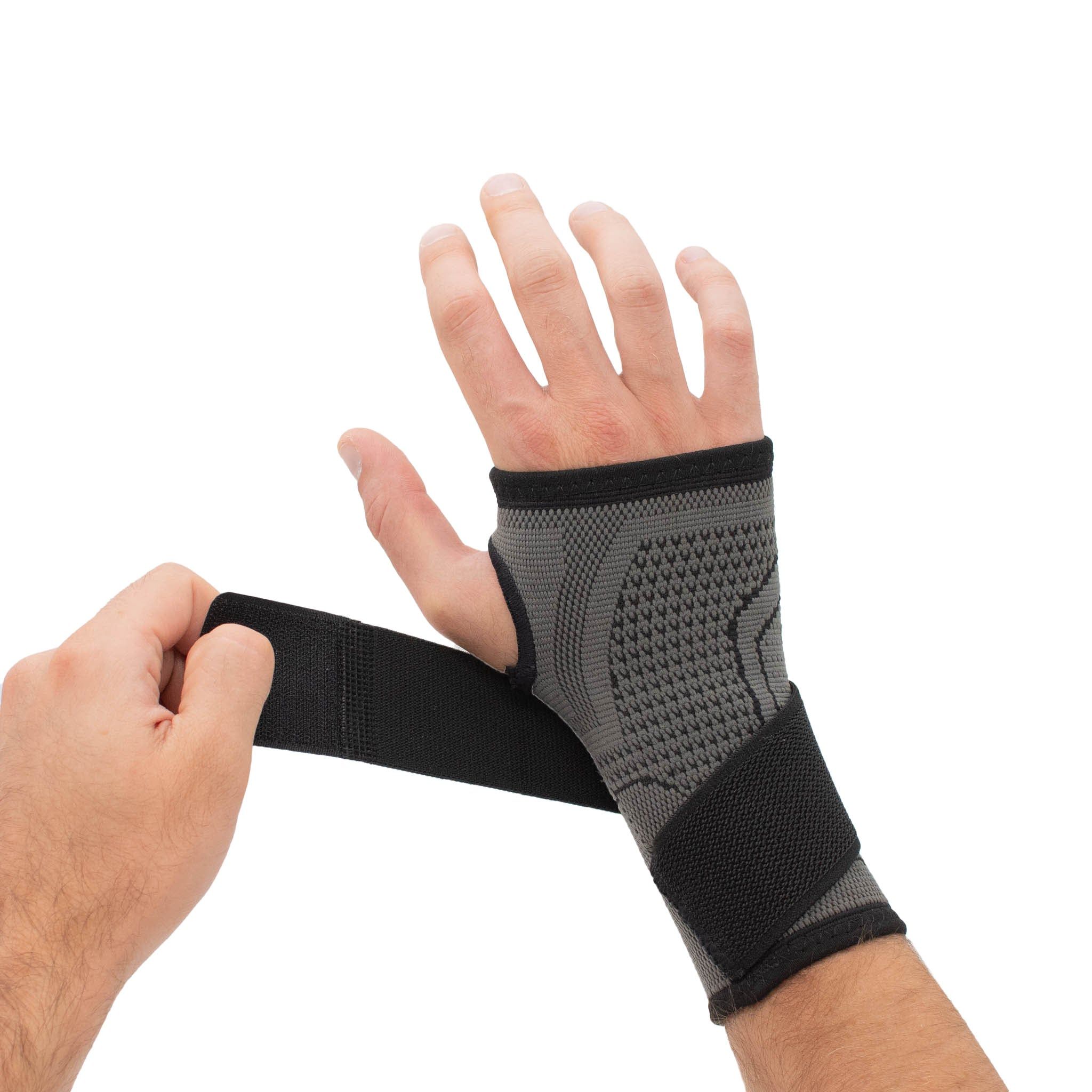 Handgelenkbandage mit Fixierungsgurt. Grau-schwarzes Textil. Hand mit Bandage, Klettverschluss wird geschlossen.