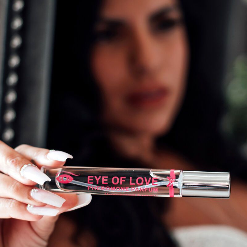Parfumflakon in Hand gehalten. Aufschrift: EYE OF LOVE PHEROMONE PARFUM. Flakon mit Sprühkopf. Frau mit langen Nägeln.