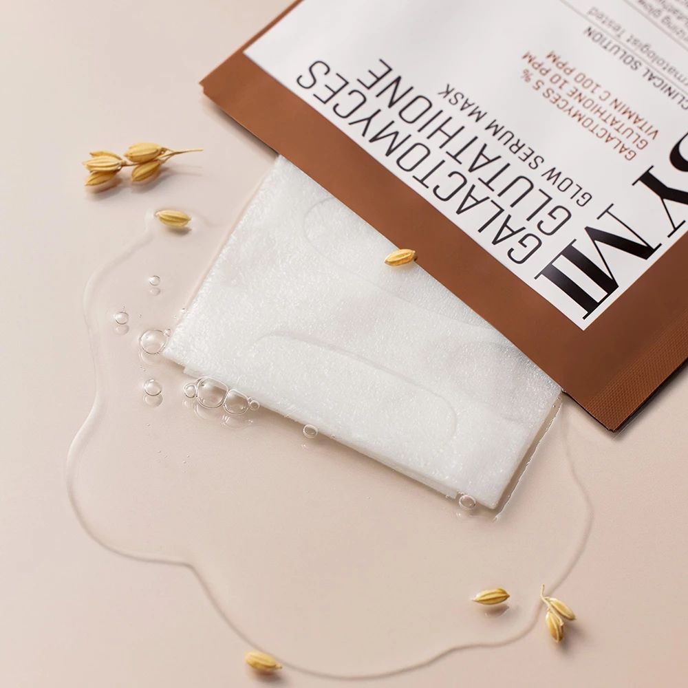 Geöffnete Produktverpackung mit Maske und Flüssigkeit. Text: SOME BY MI, Galactomyces Glutathione Glow Serum Mask. Reiskörner liegen daneben.