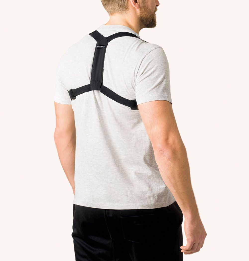 Mann trägt schwarze Haltungsstütze. Rückansicht. Haltungsstütze mit Schultergurten.