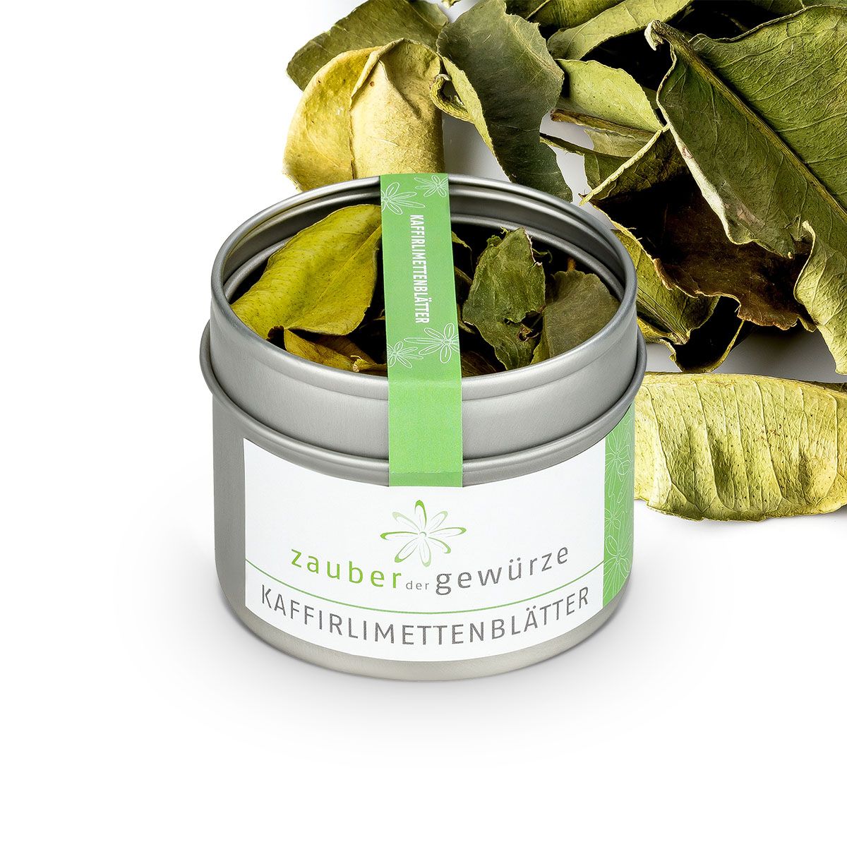 Geöffnete Dose mit Kaffirlimettenblättern. Aufkleber mit Schriftzug: Zauber der Gewürze, Kaffirlimettenblätter. Grünes Band mit Schriftzug.