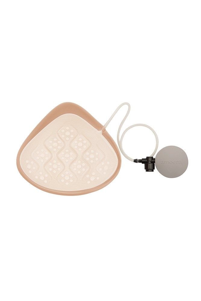 Brustprothese mit beige Oberfläche und weißer Innenseite. Pumpe und Schlauch. Graue Kugel.