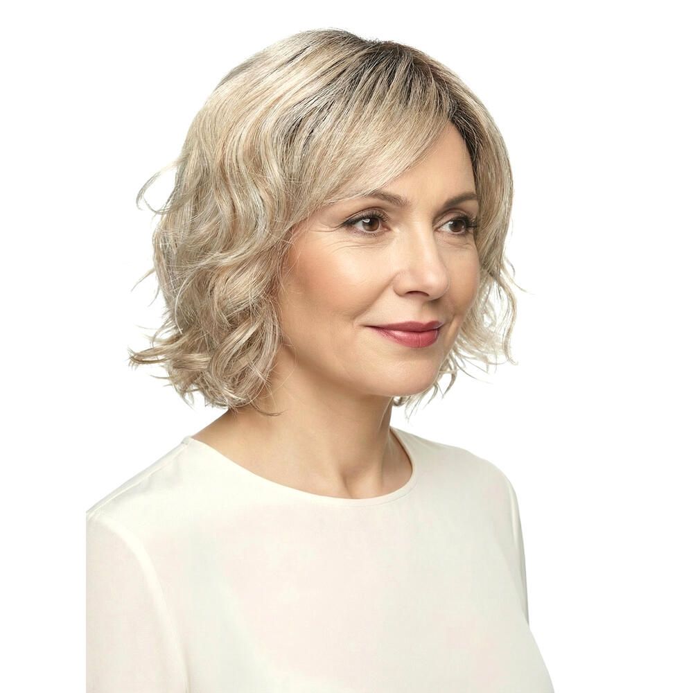 Perücke Capri von DELUXE. Blond gewellt, mit Pony. Frau mit Perücke, diagonale Ansicht.