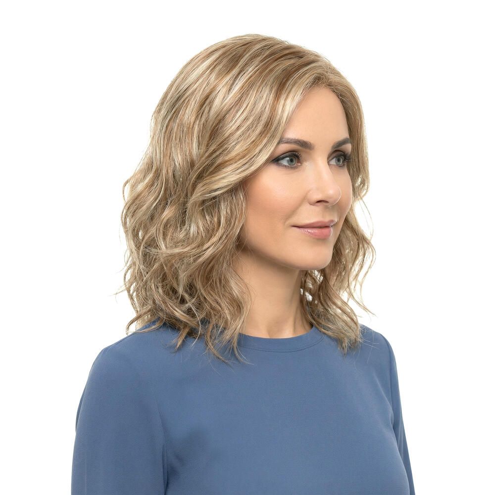 Frau mit blond gewellter Perücke. Dreiviertelansicht. Die Perücke hat blonde und hellbraune Strähnen.