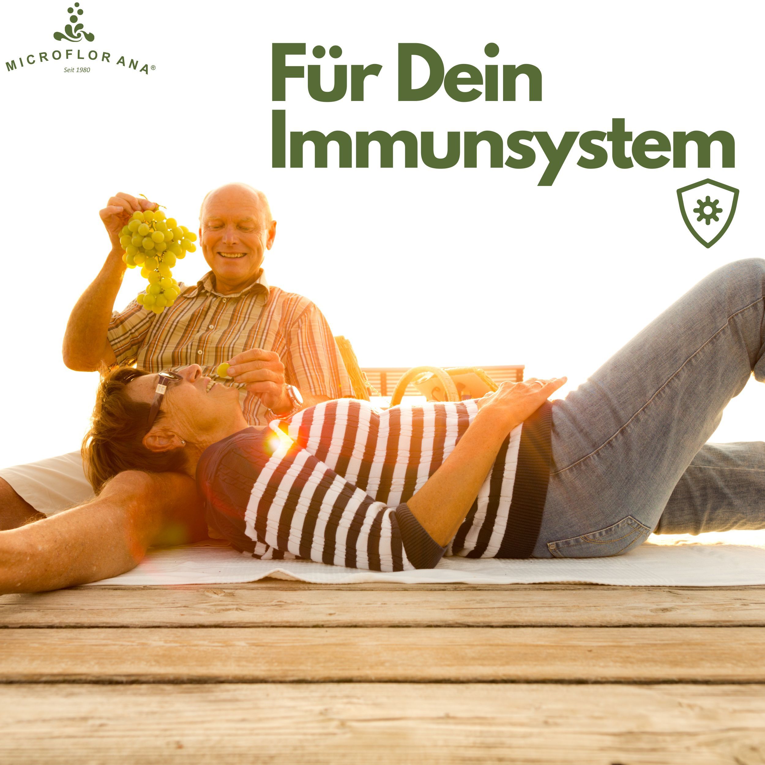 Älteres Paar beim Picknick. Mann gibt Frau Trauben. Text: Für Dein Immunsystem. Logo: MICROFLORANA®.