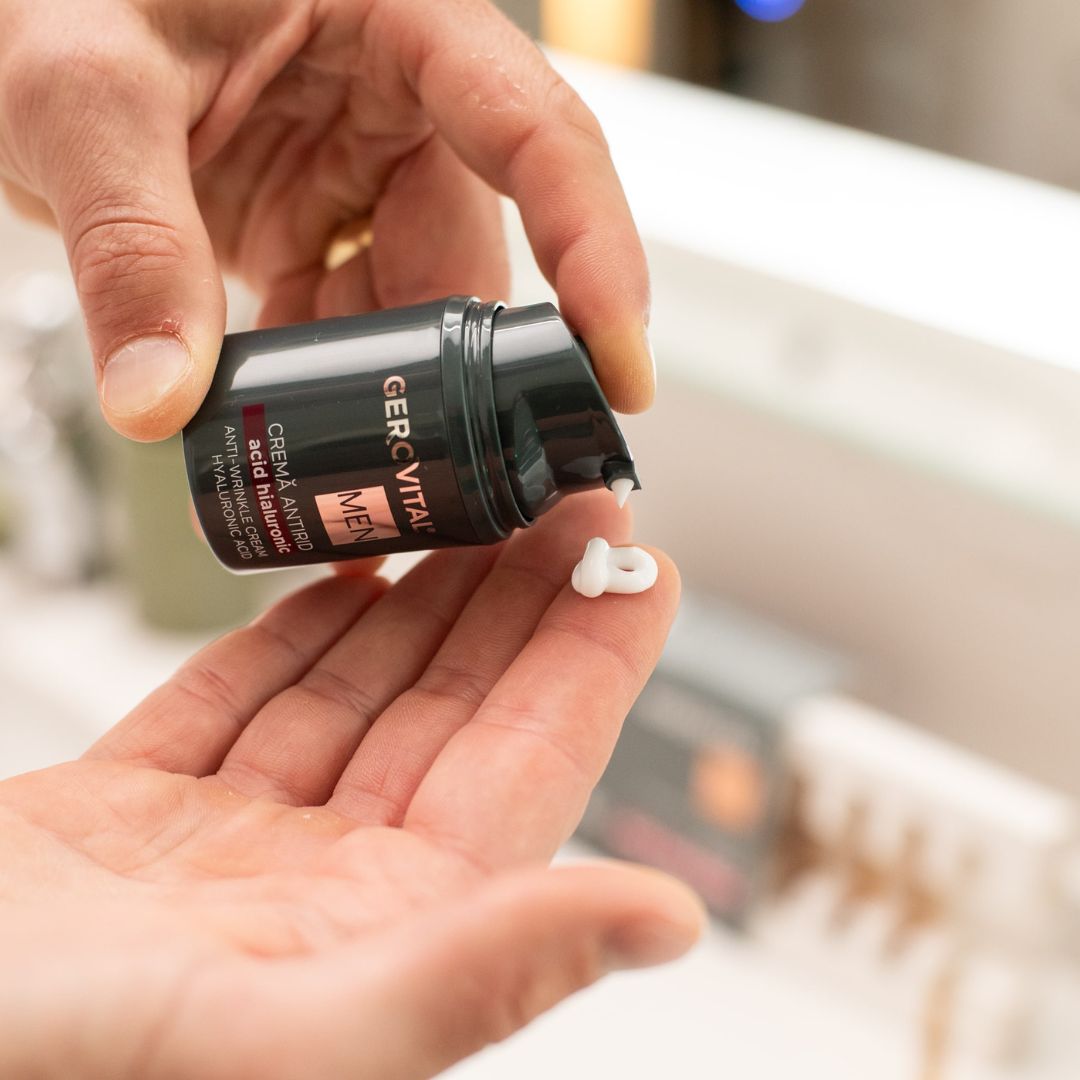 Hände halten eine dunkelgrüne Creme-Flasche. Creme wird aus dem Spender entnommen. Aufschrift: Gerovital MEN, Crema Antirid, Acid Hialuronic, Anti-Wrinkle Cream.