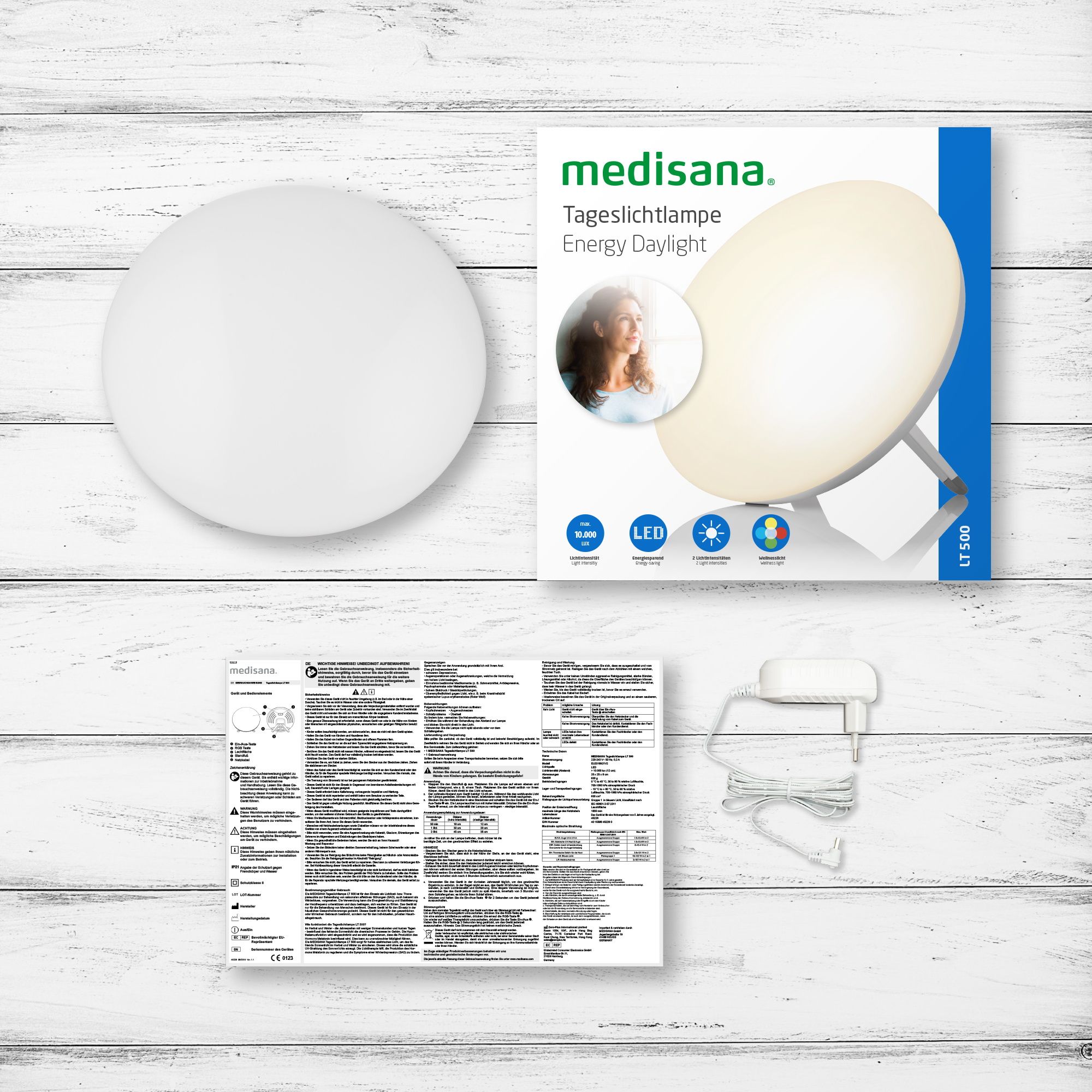 Verpackung einer medisana Tageslichtlampe mit Zubehör: Lampe, Netzteil, Anleitung.