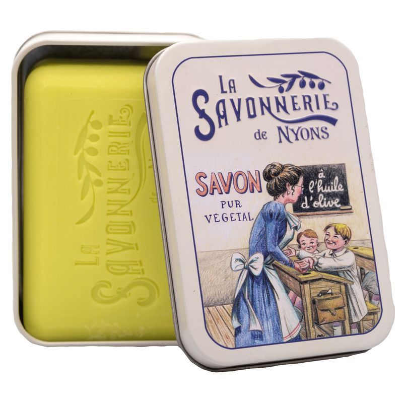 Geöffnete Metallbox mit Seife. Seife gelb. Aufdruck auf der Box: La Savonnerie de Nyons, Savon pur végétal. Motiv: Lehrerin und Kinder.
