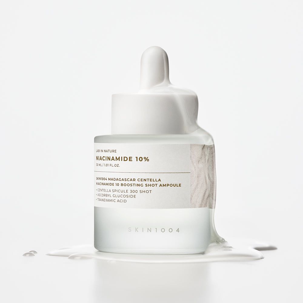 SKIN1004 Ampulle mit Niacinamid 10%, umflossen von einer weißen Flüssigkeit.