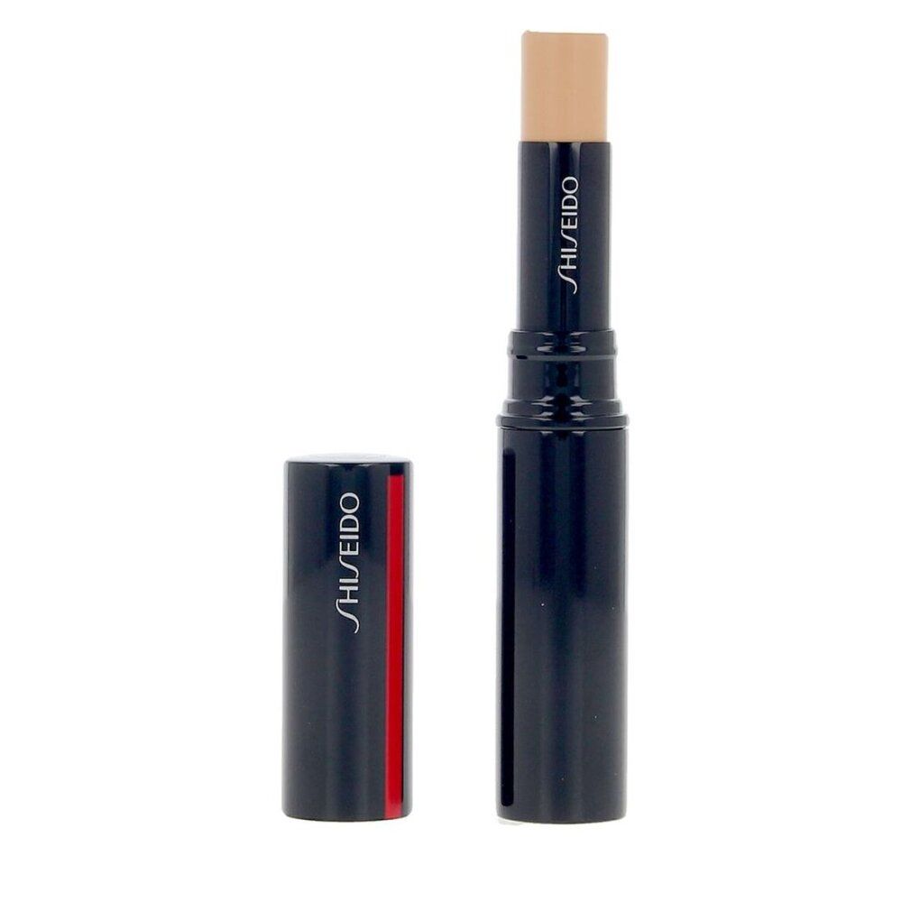 Concealer-Stick, dunkelblau mit rotem Streifen. Deckel daneben. Produktname und Marke: SHISEIDO. Creme-farbener Stift.