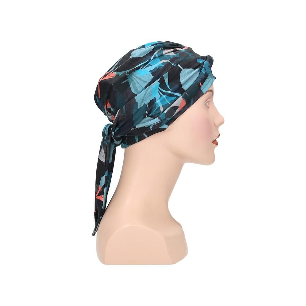 Turban Letti, floral bedruckt, auf einer Büste. Farben: Schwarz, Türkis, Rosa. Stoff mit Falten. Seitenansicht mit Schleife.