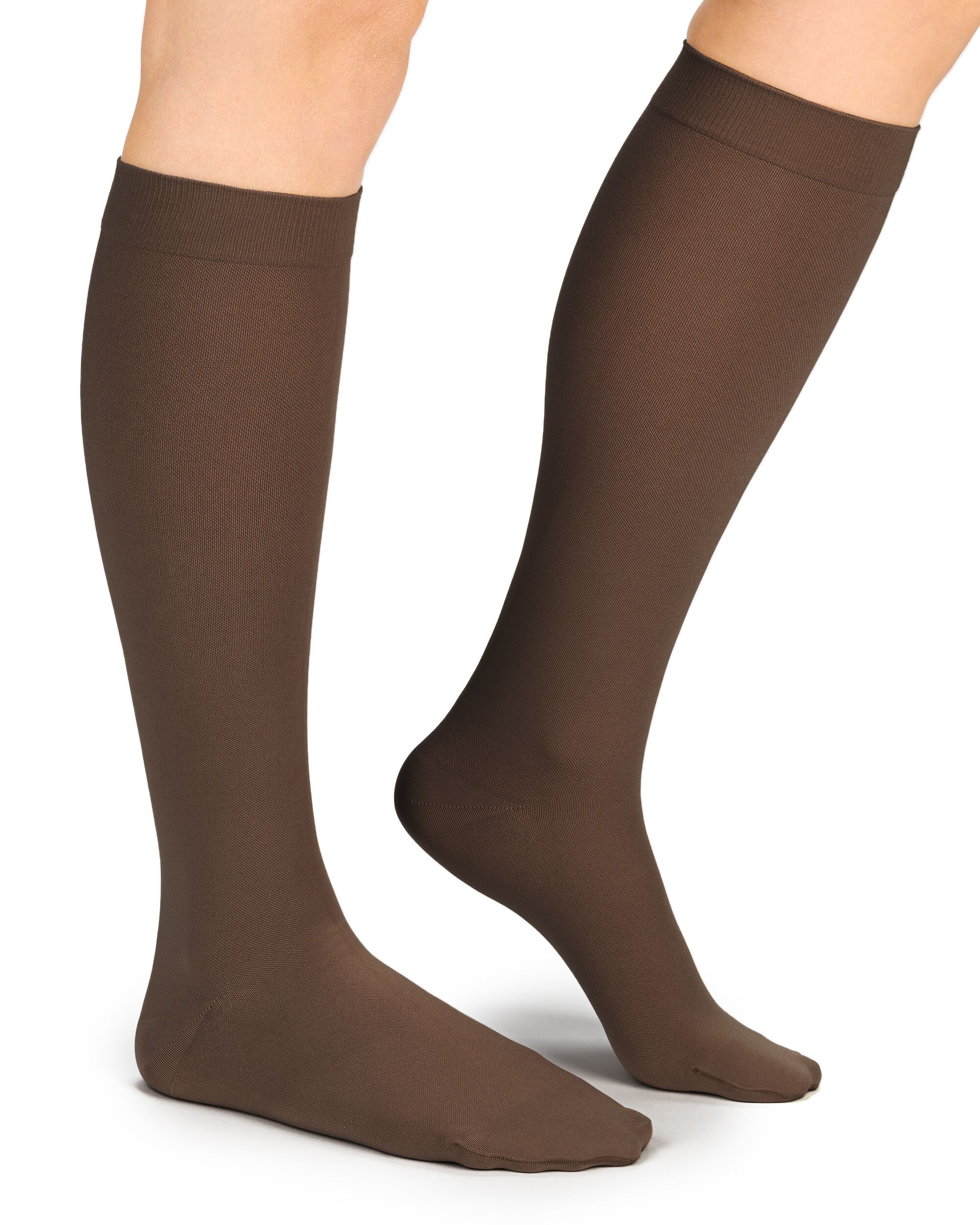 Braune Kompressionsstrümpfe, Kniestrümpfe, an Beinen getragen. Blick von der Seite, Füße auf weißem Hintergrund.