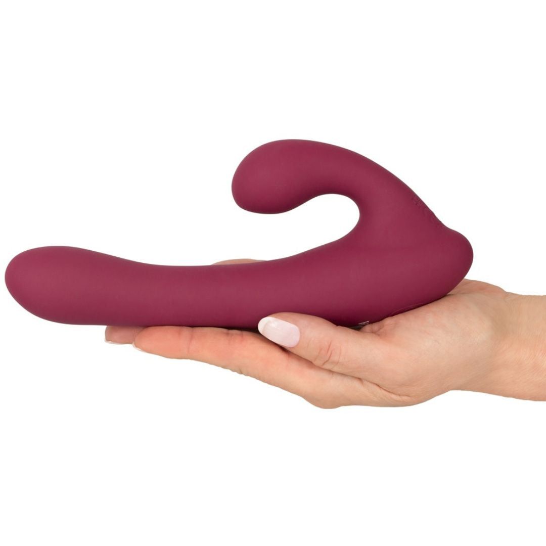 Weinroter Vibrator in einer Hand gehalten. Der Vibrator hat eine geschwungene Form.