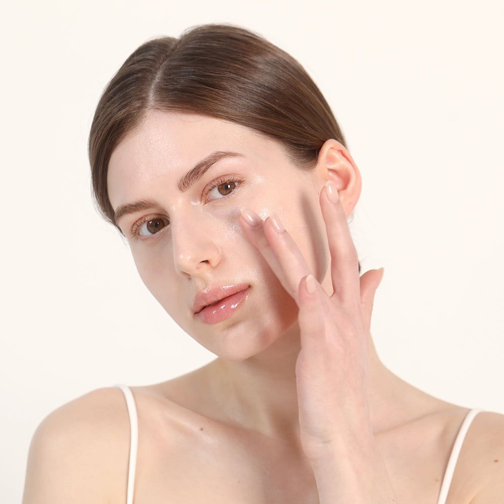 Frau trägt eine transparente Creme auf ihr Gesicht auf.