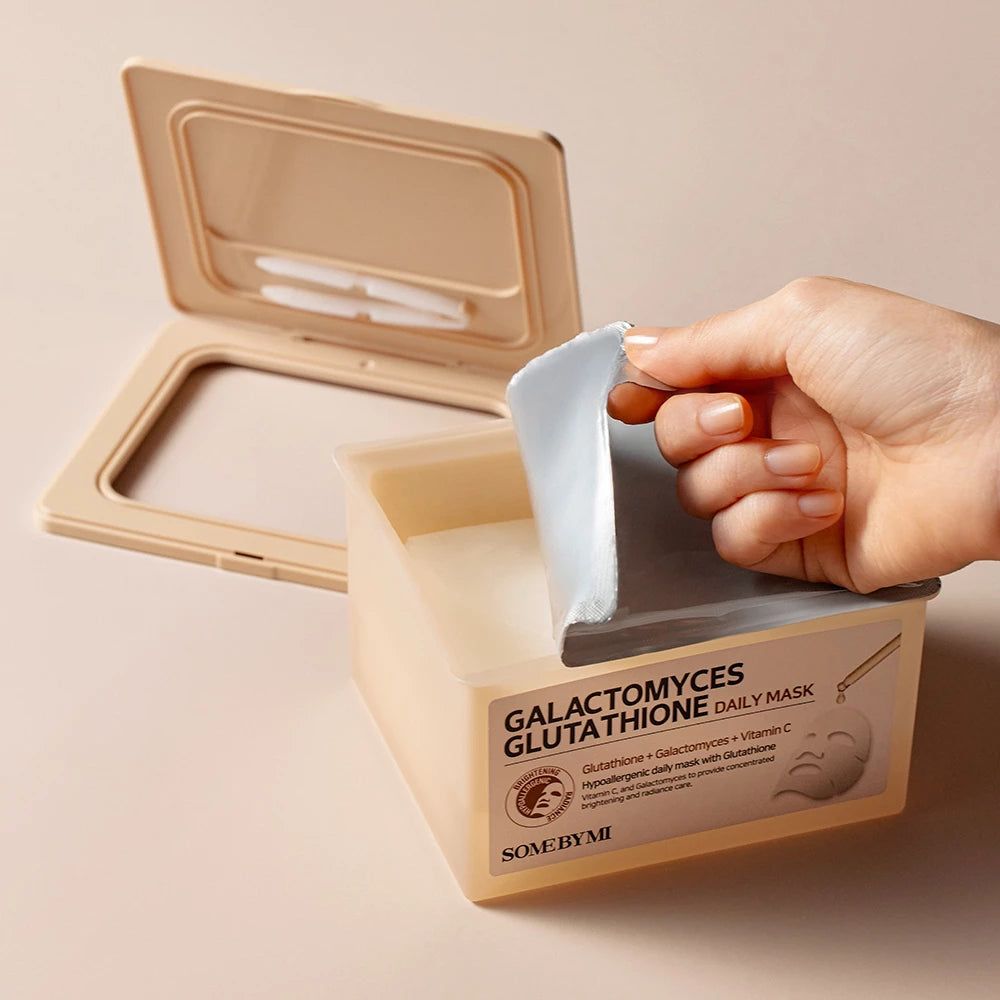 Beige Behälter, Deckel geöffnet. Hand entnimmt Maske. Aufschrift: Galactomyces Glutathione Daily Mask.