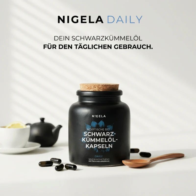 Schwarzkümmelöl Kapseln in schwarzer Keramikdose mit Korkverschluss, daneben Kapseln, eine Teetasse und eine Teekanne.