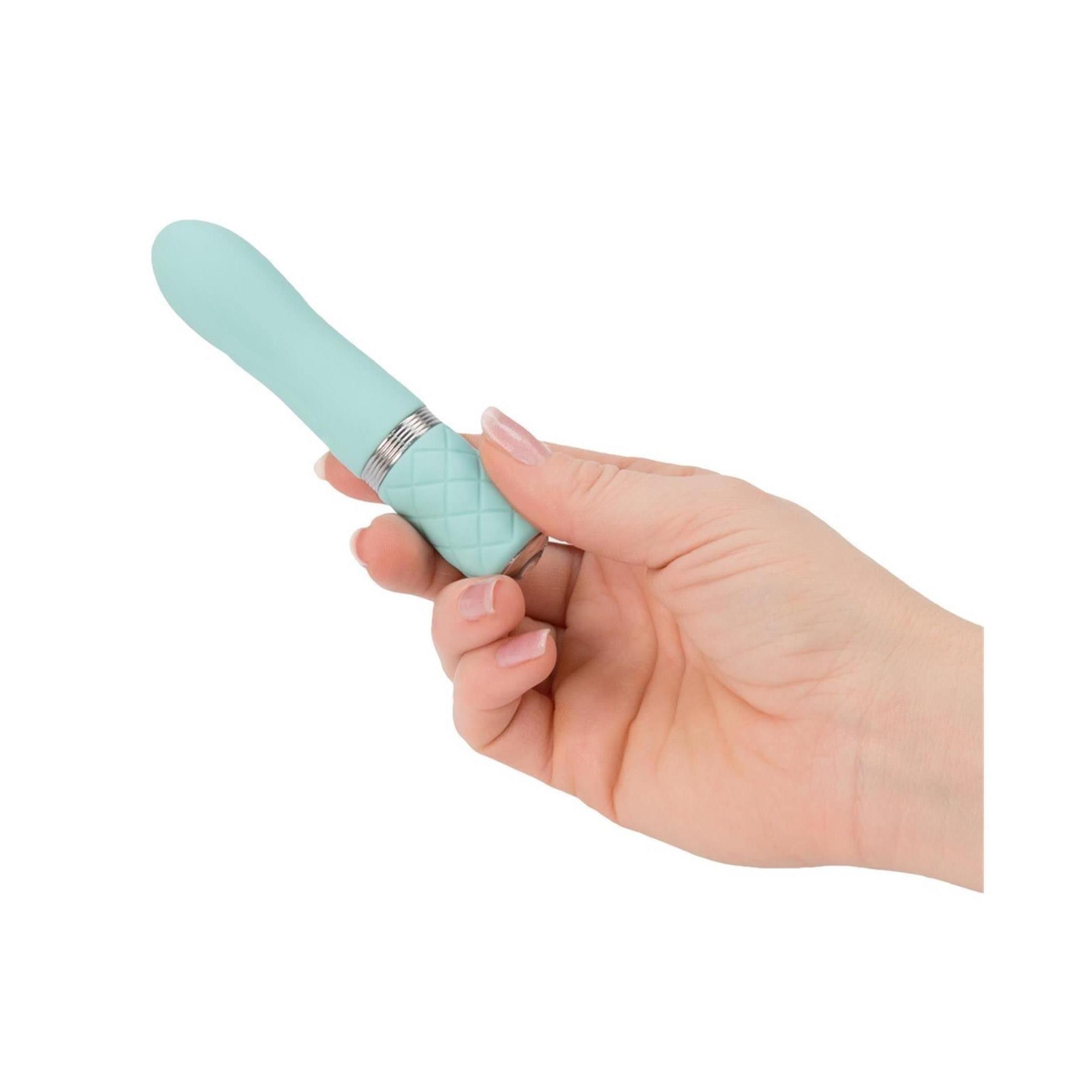 Türkisfarbener Vibrator in einer Hand gehalten. Silberner Ring und rautenförmiges Muster am Griff.