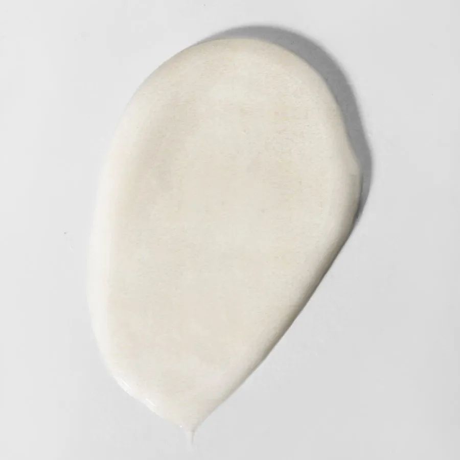 Heller, cremiger Klecks auf weißem Hintergrund. Textur des Produkts sichtbar.