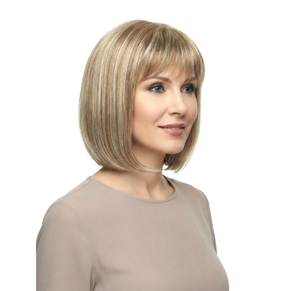 Perücke mit kurzem, blondem Haar und Pony. Die Frau trägt ein beiges Oberteil. Nahaufnahme.