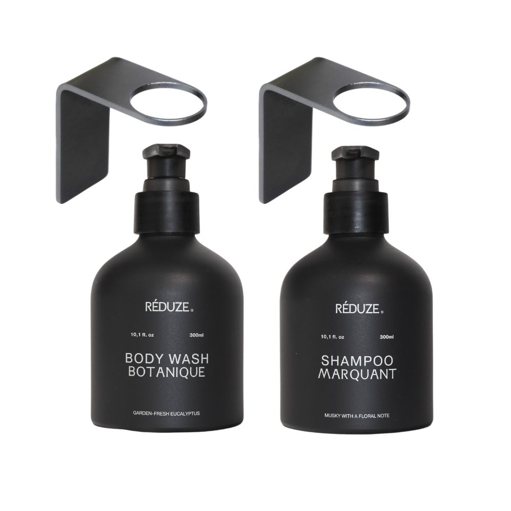 Zwei schwarze Flaschen mit Wandhalterungen. Aufschrift: RÉDUZE, Body Wash Botanique, Shampoo Marquant.