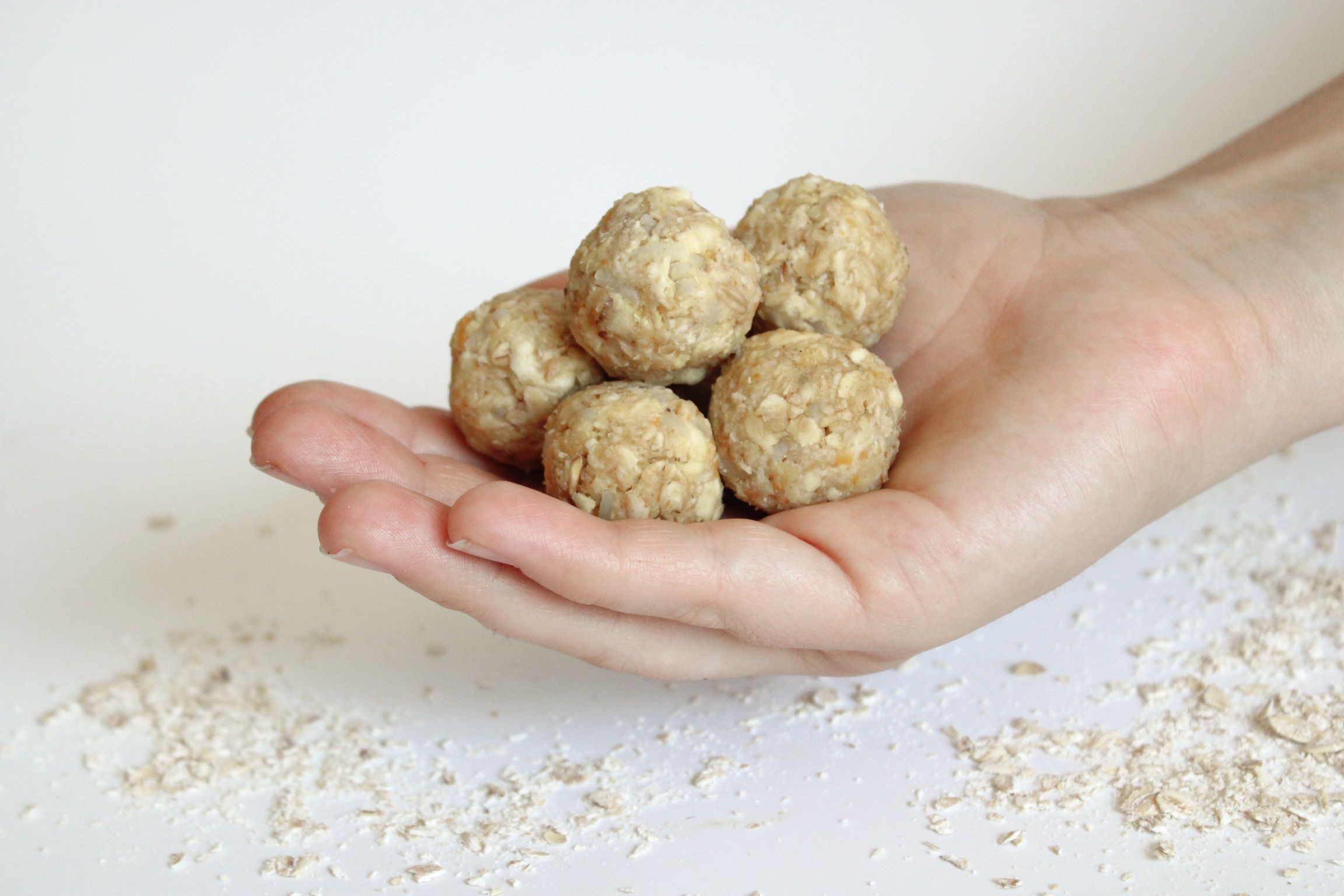 Hand mit mehreren Kugeln aus Getreideflocken. Streusel auf weißem Untergrund.
