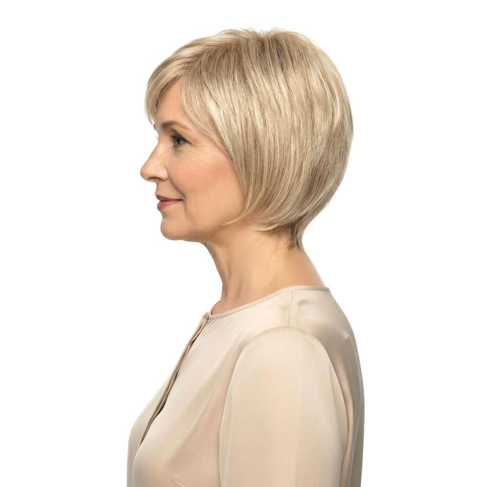 Blond gefärbte Perücke mit kurzem, gewelltem Haar. Seitenansicht einer Frau mit Perücke. Hellbeige Oberteil.