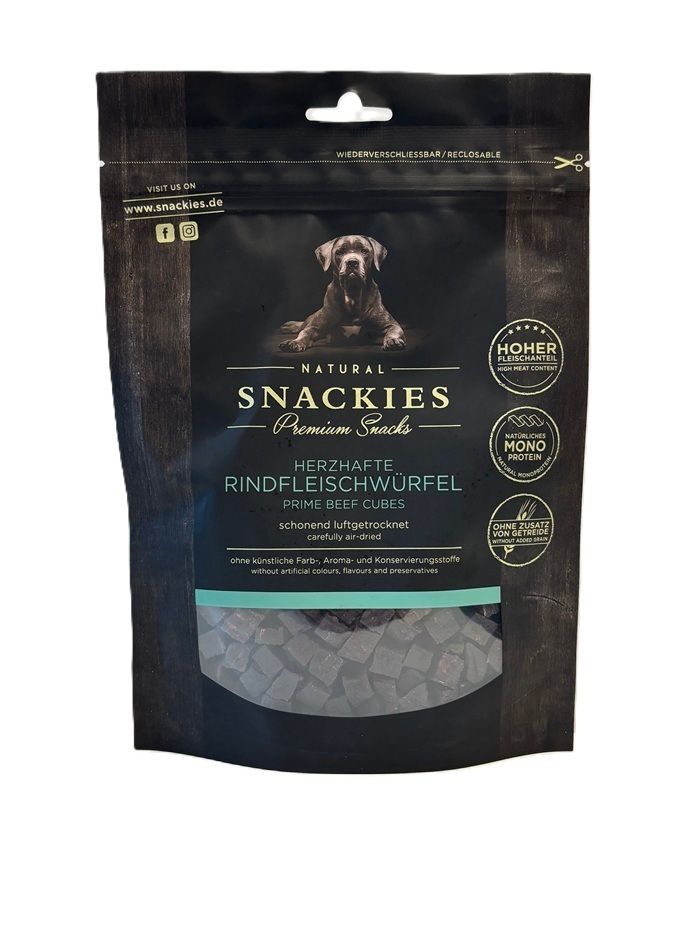 Verpackung mit Snackies Herzhafte Rindfleischwürfel. Schwarze Tüte mit Produktbild, Logo und Text. Sichtfenster mit Würfeln.