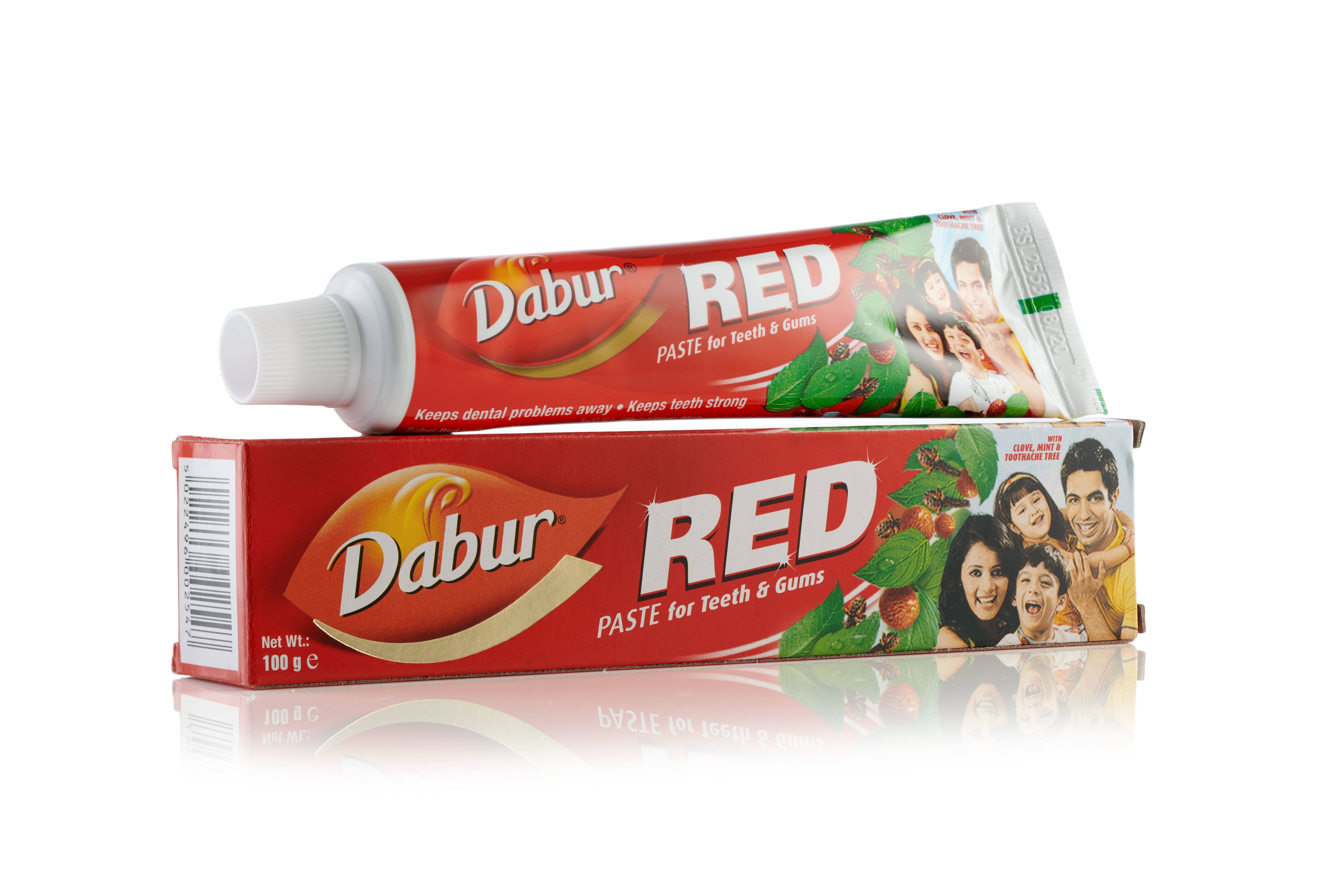 Rote Zahnpasta-Tube und Schachtel. Aufschrift: Dabur RED PASTE for Teeth & Gums. Familienfoto auf der Schachtel.