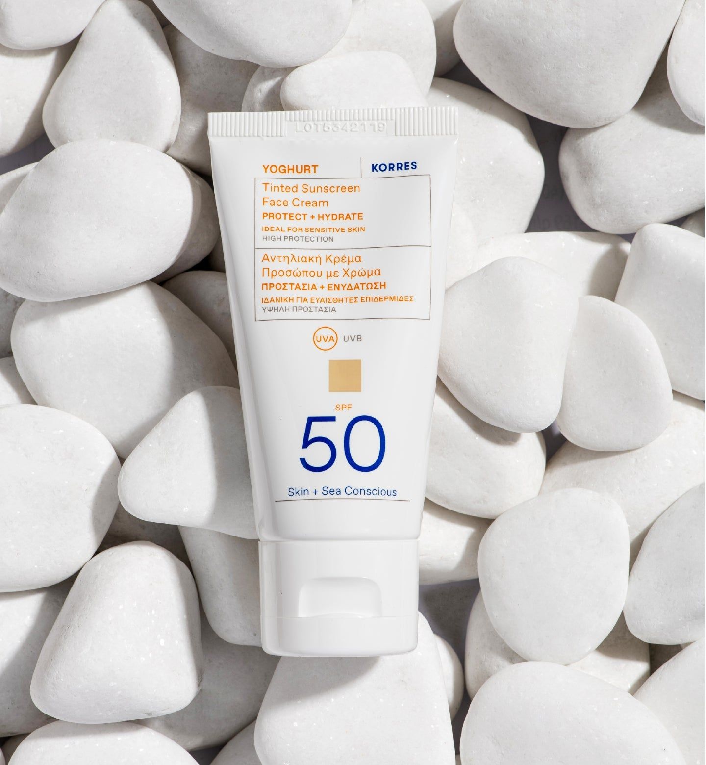 KORRES Yoghurt Getönte Sonnencreme SPF50. Tube auf weißen Steinen. Produktinformationen, SPF 50.