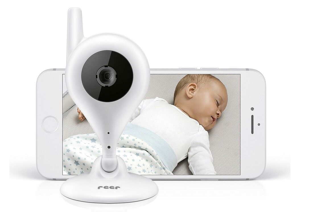 Weiße Babykamera mit Smartphone, das ein schlafendes Baby zeigt. Die Kamera hat eine Antenne und einen Standfuß.