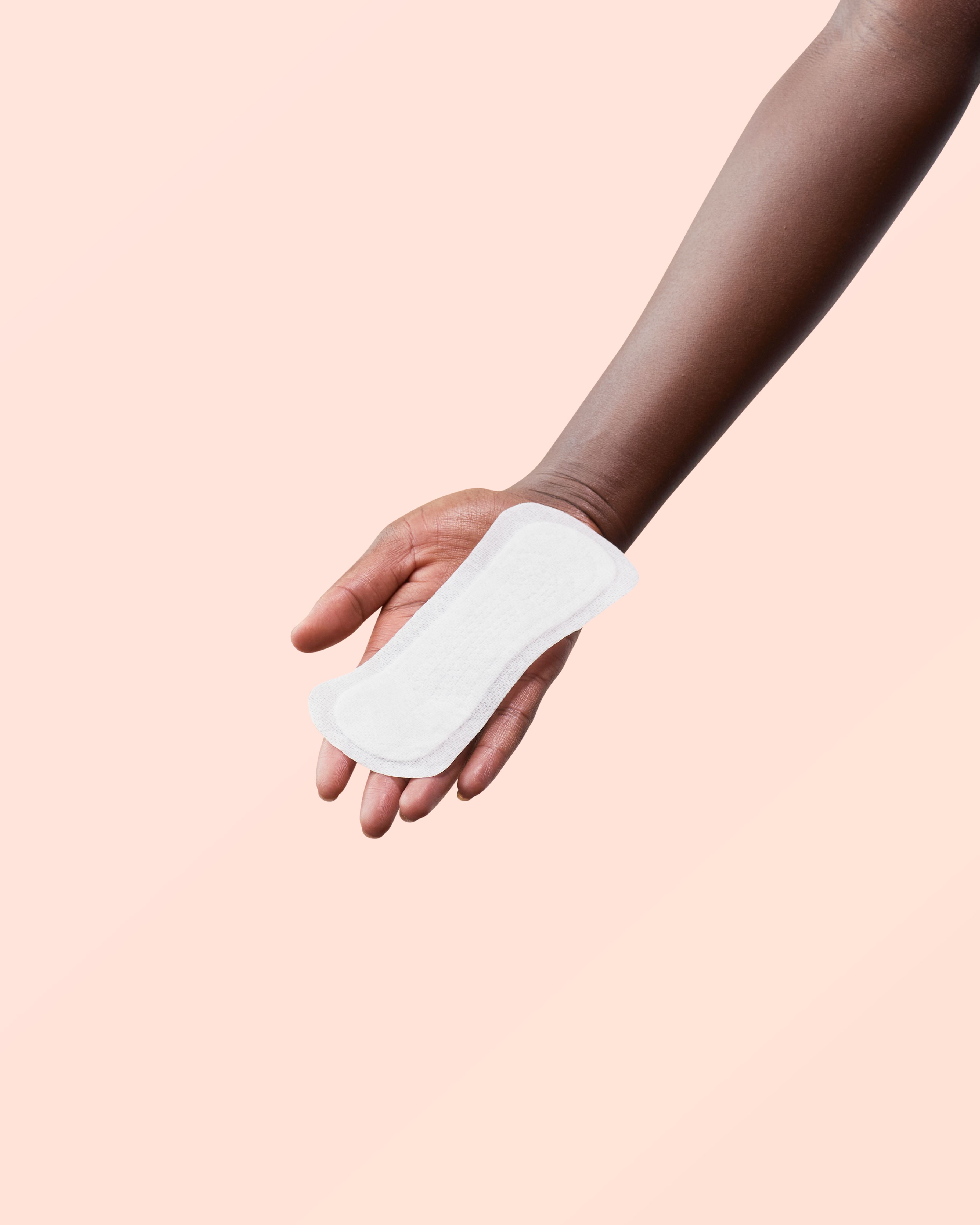 Hand hält eine weiße Slipeinlage. Auf rosa Hintergrund.