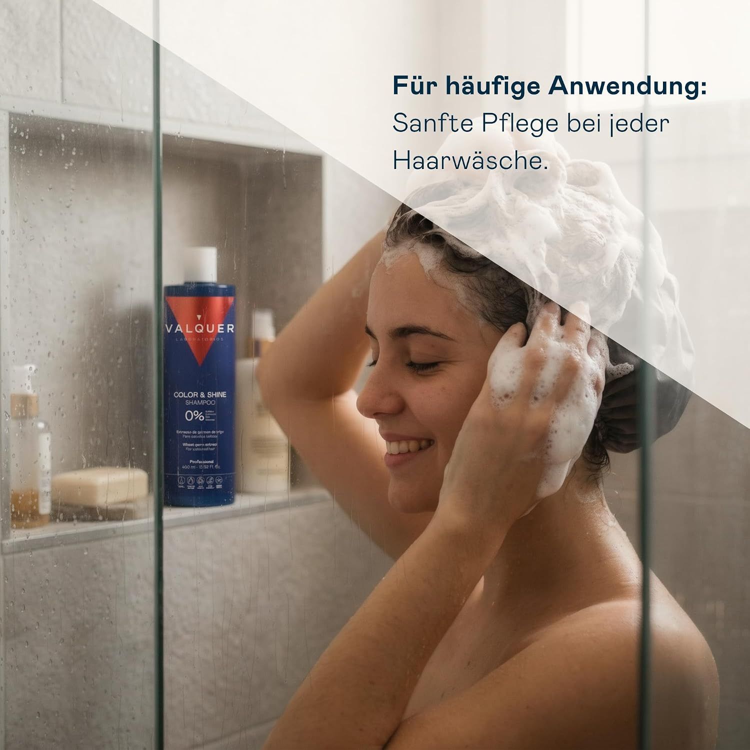 Eine Frau wäscht sich die Haare mit Schaum in der Dusche, "Valquer Color & Shine" Flasche sichtbar.
