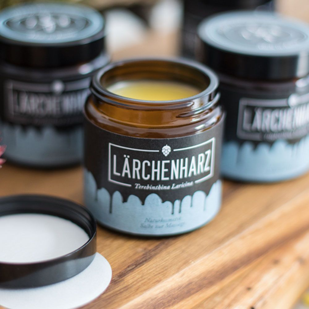Geöffnete braune Gläser mit gelblicher Salbe. Aufschrift: LÄRCHENHARZ, Terebinthina Laricina. Naturkosmetik Salbe zur Massage.