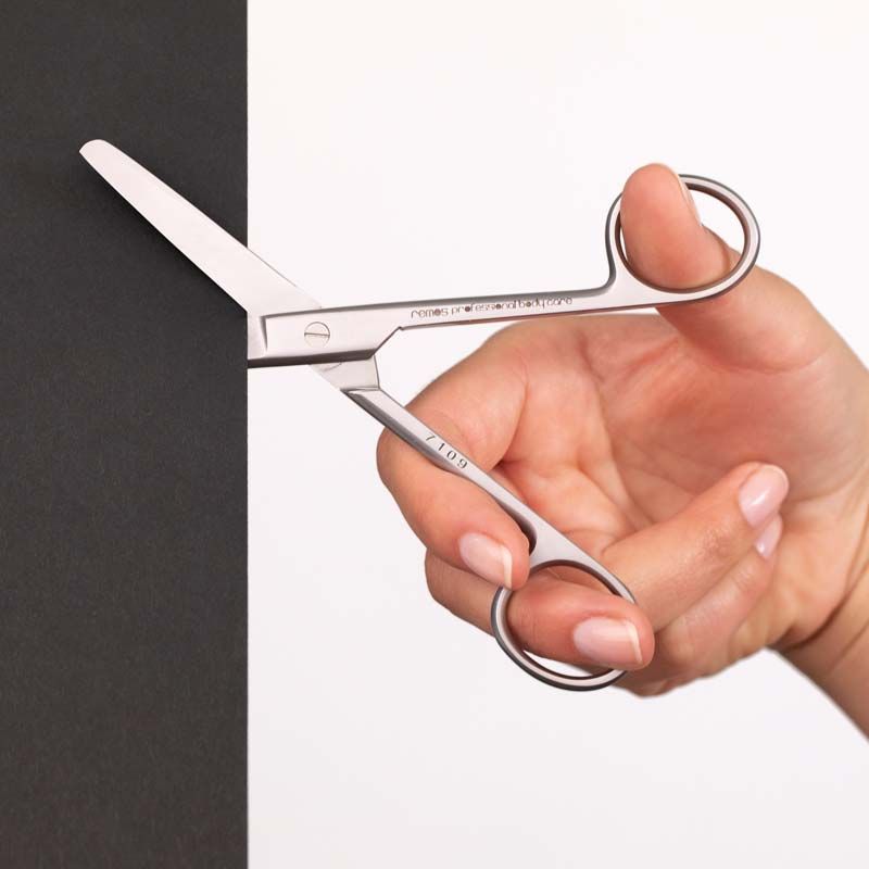 Schere mit gerader Schneide in Hand gehalten. Metall, silberfarben. Griffe mit Fingerlöchern.