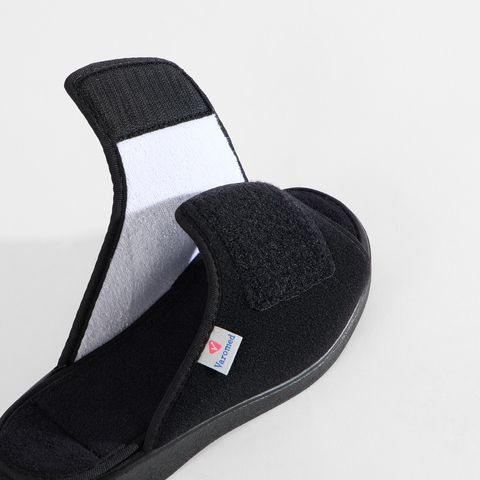Schwarze Pantoletten mit Klettverschluss und offenem Zehenbereich.