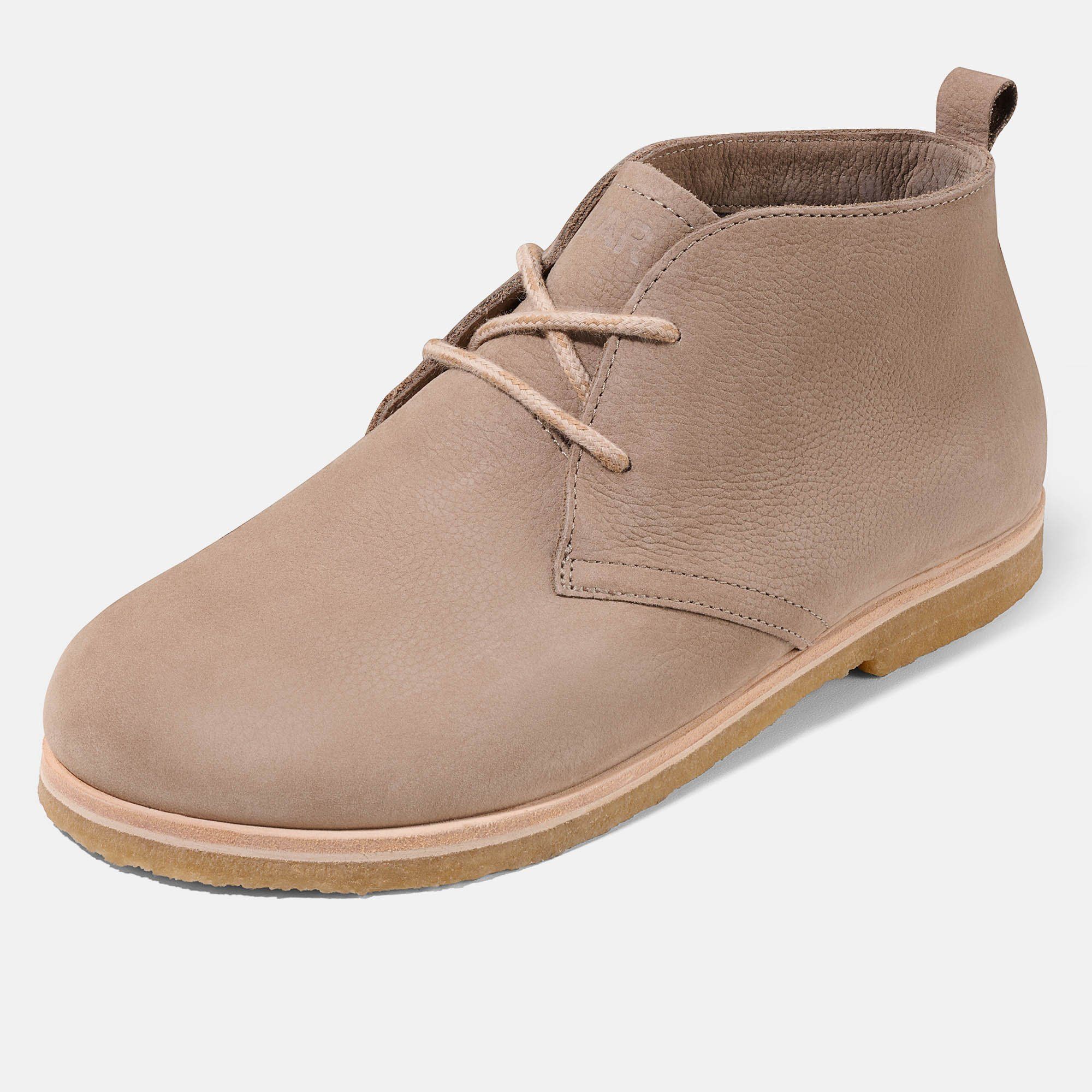 Beige Stiefelette mit Schnürsenkeln. Hellbraune Sohle. Obermaterial aus Leder. Auf hellem Hintergrund.