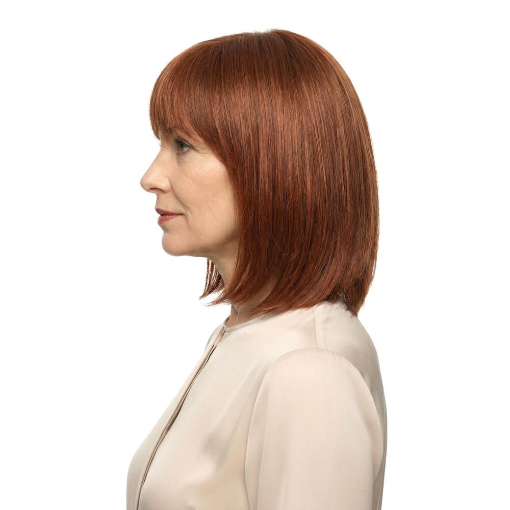 Profil einer Frau mit roter Perücke mit Pony und schulterlangem Schnitt. Sie trägt ein helles Oberteil. Weißer Hintergrund.