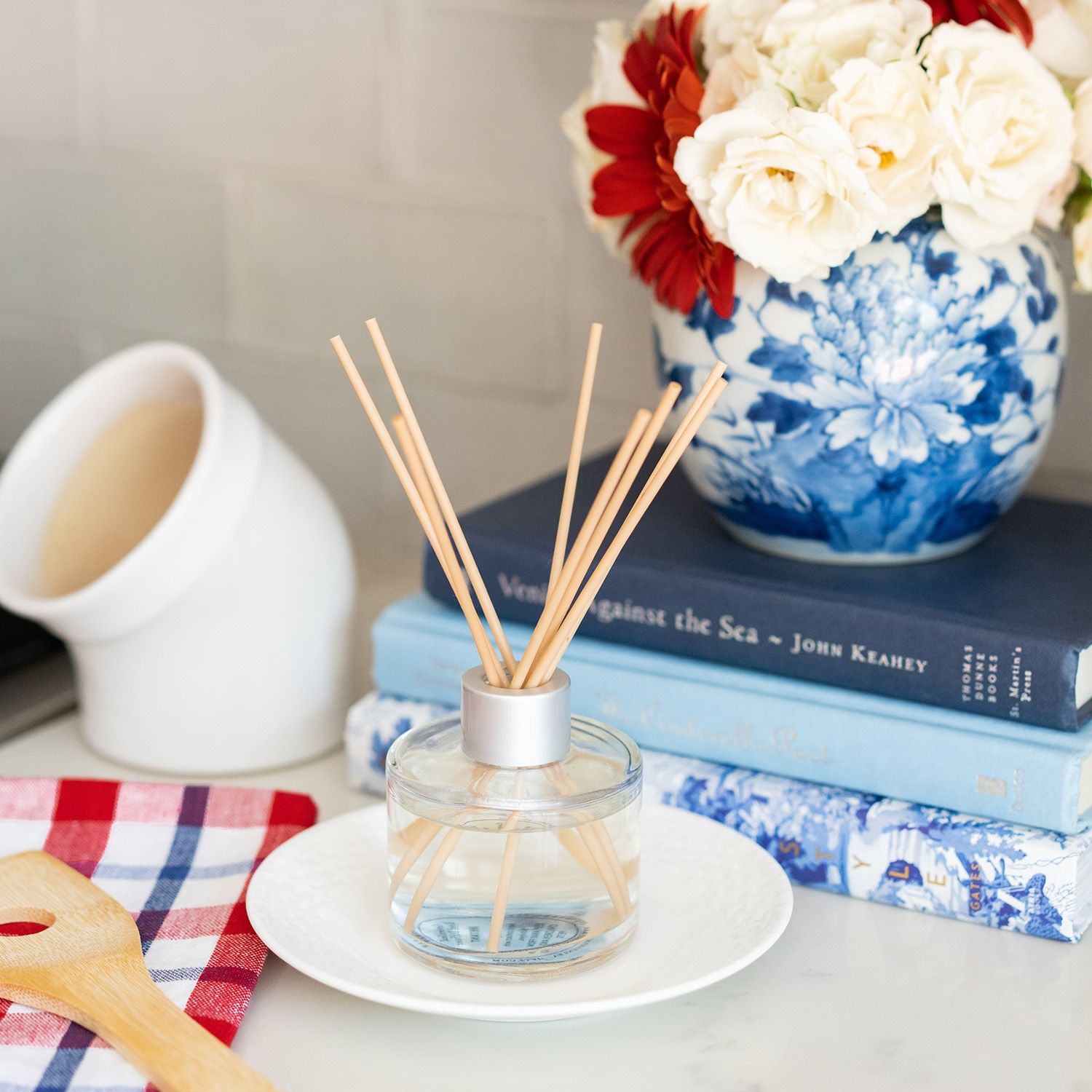 Duft-Diffusor auf einem Tisch neben Büchern und einer Blumenvase.
