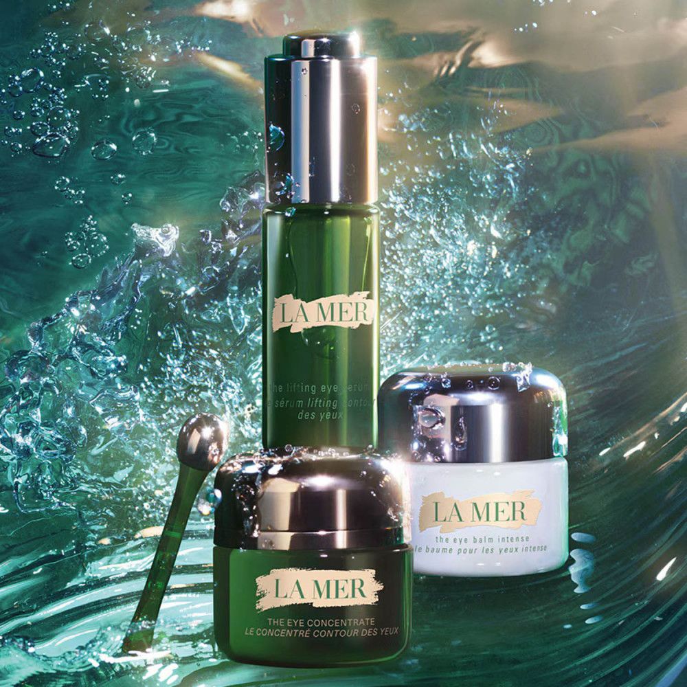 Drei Produkte von La Mer: Augenbalsam, Serum und Augenkonzentrat. Mit einem Applikator. Im Wasser platziert.