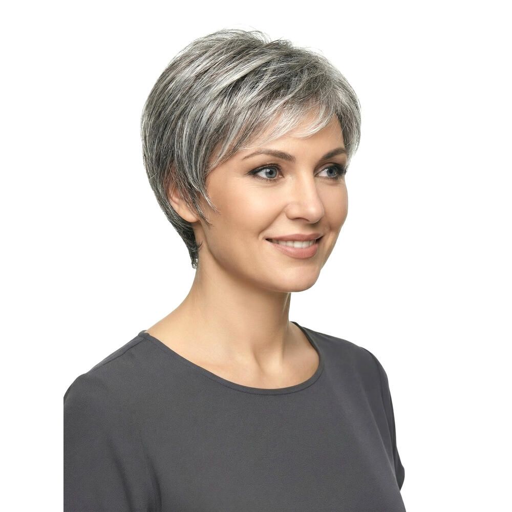Nahaufnahme einer Frau mit kurz geschnittener, grau-melierter Perücke. Graues Oberteil. Lächelt.