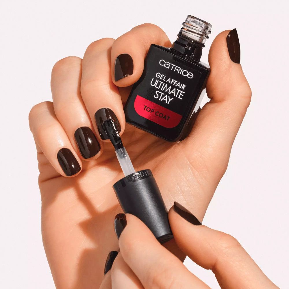 Hände mit lackierten Nägeln halten eine Flasche. Aufschrift: Catrice, Gel Affair, Ultimate Stay, Top Coat.